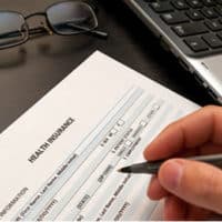 Image of person filling out a health insurance form