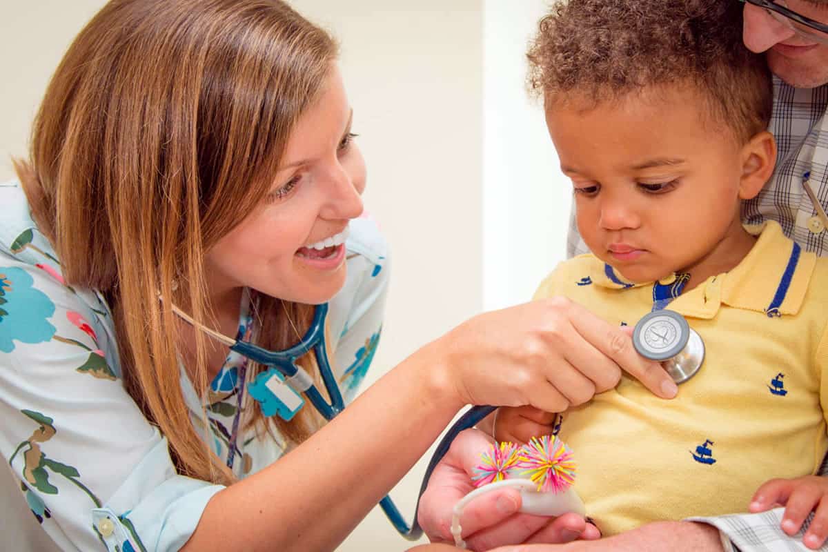 Female Doctor examining toddler as Dad looks on